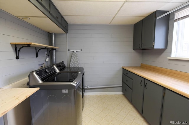 clothes washing area featuring washer and clothes dryer, cabinets, and wood walls