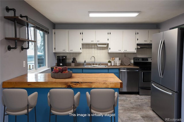 5063 W 61st Ave, Arvada, CO 80003 - kitchen with stainless steel appliances, a sink, under cabinet range hood, tasteful backsplash, and white cabinetry