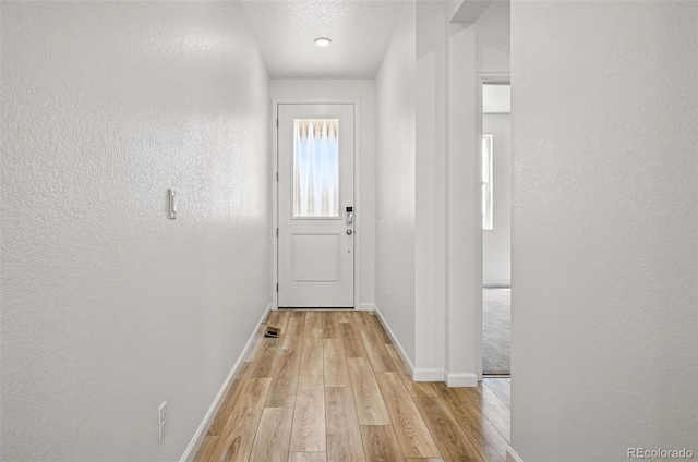 3401 N Denali St, Aurora, CO 80019 - doorway to outside with baseboards, light wood-style flooring, and a textured wall