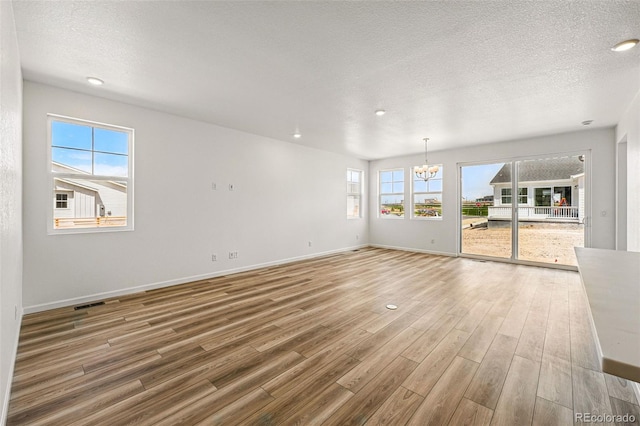 3401 N Denali St, Aurora, CO 80019 - spare room featuring a chandelier, wood finished floors, baseboards, a textured ceiling, and recessed lighting