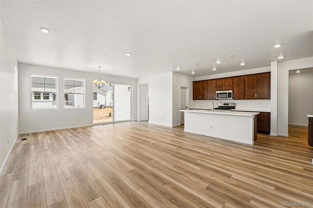 3401 N Denali St, Aurora, CO 80019 - unfurnished living room featuring a chandelier, recessed lighting, baseboards, light wood-style flooring, and a sink