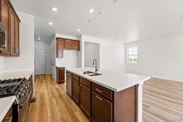 3401 N Denali St, Aurora, CO 80019 - kitchen with a sink, appliances with stainless steel finishes, light wood-style floors, a center island with sink, and light countertops