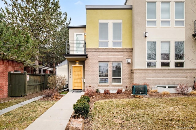 view of front of house with a front lawn, fence, brick siding, and stucco siding