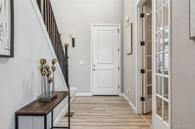 doorway to outside featuring visible vents, light wood-style flooring, baseboards, and stairs