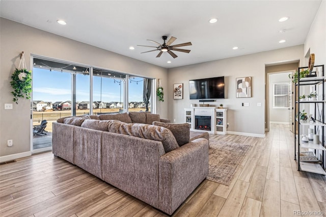 living area featuring a glass covered fireplace, visible vents, light wood-style flooring, and recessed lighting