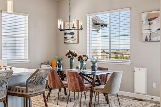 dining space featuring visible vents, baseboards, a notable chandelier, and wood finished floors