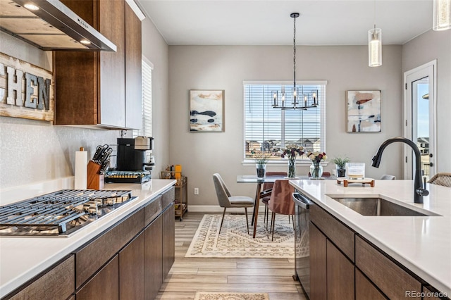 kitchen with range hood, appliances with stainless steel finishes, light countertops, and a sink