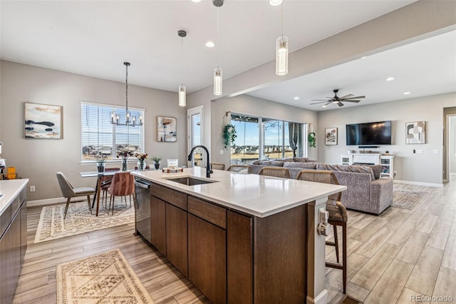 kitchen featuring light wood-type flooring, dishwasher, light countertops, and a sink