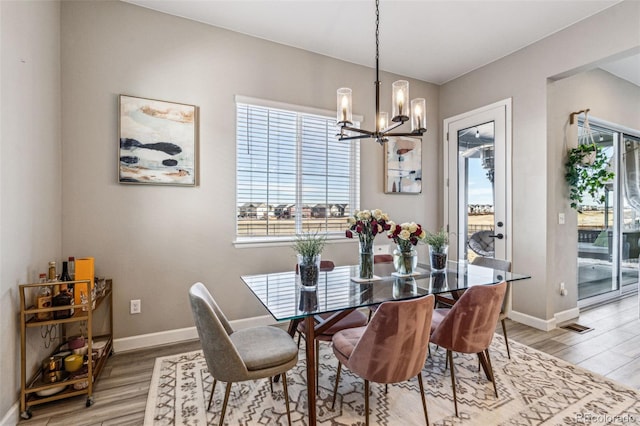 dining area featuring light wood-style floors, a chandelier, visible vents, and baseboards