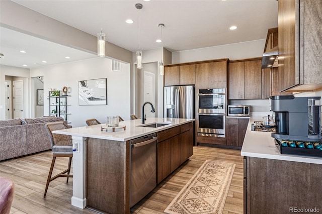 kitchen with light countertops, stainless steel appliances, a sink, and open floor plan