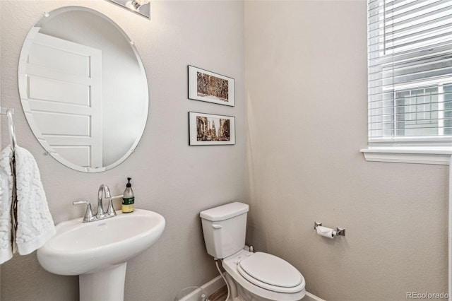 bathroom with toilet, baseboards, and a sink