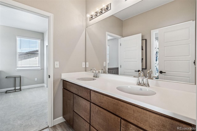 bathroom with a sink, baseboards, and double vanity