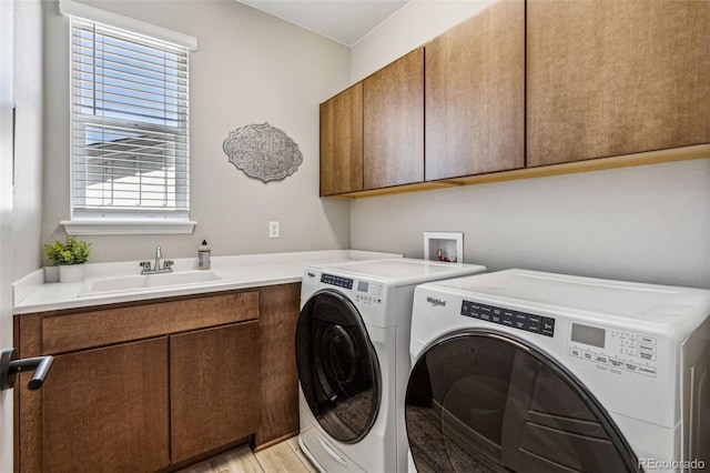 laundry room with light wood-type flooring, washing machine and dryer, cabinet space, and a sink