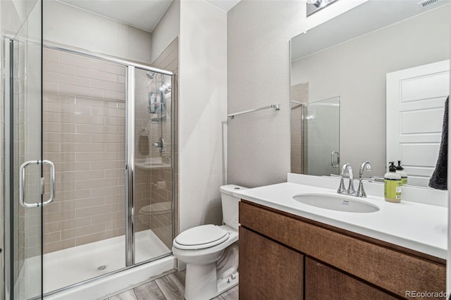 bathroom featuring toilet, a shower stall, visible vents, and wood finished floors