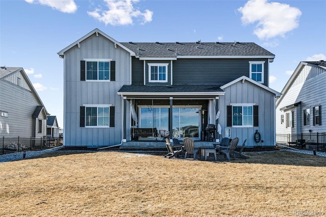 rear view of property with a yard, board and batten siding, and fence private yard