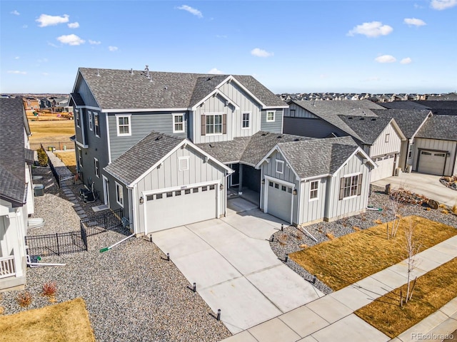 view of front of property featuring driveway, fence, board and batten siding, and roof with shingles