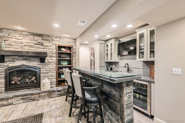 14118 Whitney Cir, Broomfield, CO 80023 - indoor wet bar featuring wine cooler, light wood-style flooring, recessed lighting, backsplash, and a fireplace