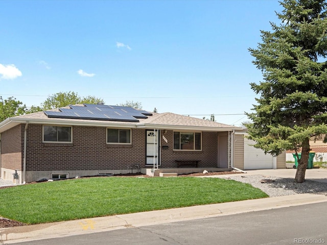 single story home featuring a front lawn, solar panels, brick siding, and driveway
