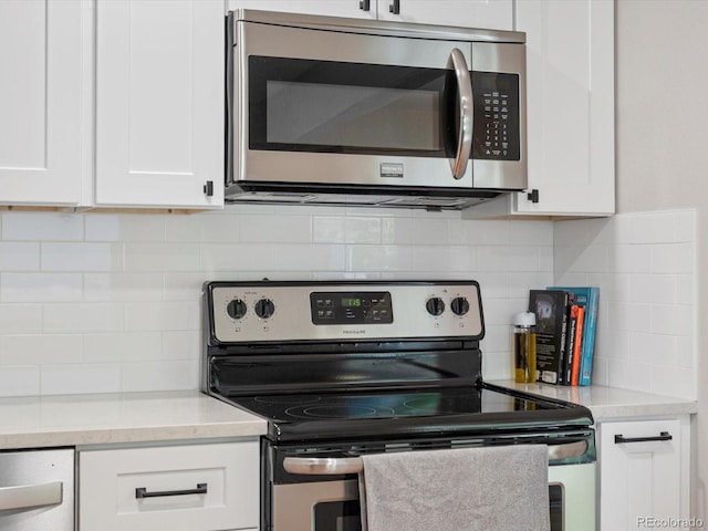 kitchen featuring stainless steel appliances, white cabinetry, backsplash, and light countertops