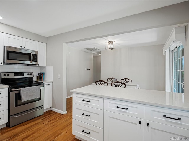kitchen with appliances with stainless steel finishes, light countertops, light wood-style floors, white cabinetry, and baseboards