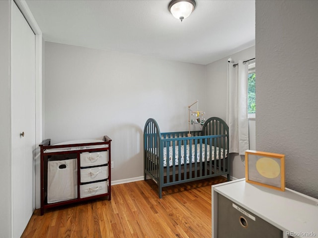 bedroom featuring light wood-style flooring and a crib
