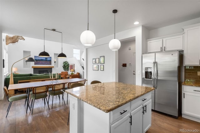 9567 Juniper Way, Arvada, CO 80007 - kitchen featuring stainless steel refrigerator with ice dispenser, a kitchen island, dark wood-style floors, stone counters, and hanging light fixtures