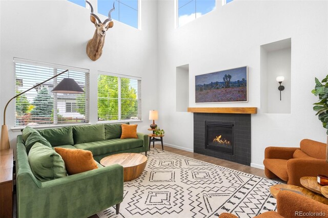 9567 Juniper Way, Arvada, CO 80007 - living area featuring a towering ceiling, wood finished floors, a glass covered fireplace, and baseboards
