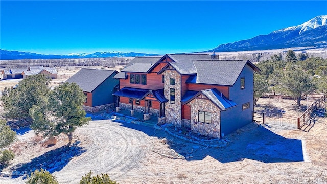 view of front of property with a mountain view, fence, driveway, stone siding, and a gate