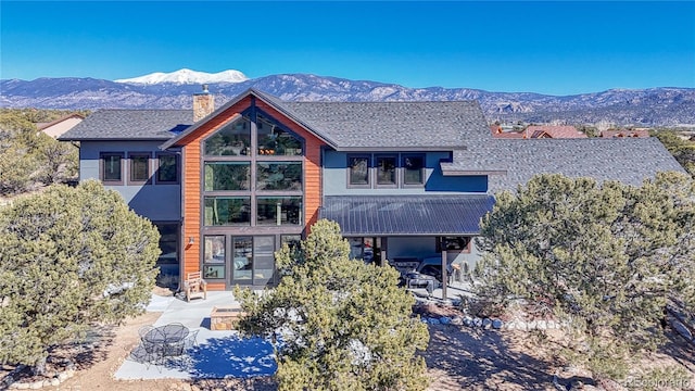 view of front facade featuring a chimney, a mountain view, metal roof, and a patio