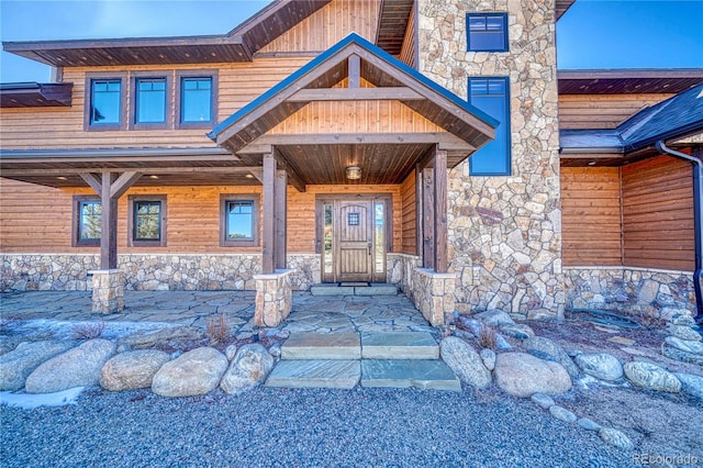 entrance to property with stone siding and a chimney