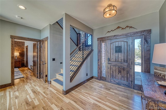 foyer entrance featuring stairs, light wood-style flooring, and baseboards