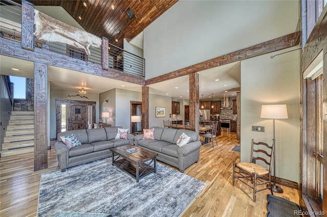 living area with stairs, hardwood / wood-style floors, a towering ceiling, and baseboards