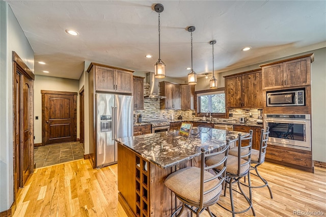 kitchen featuring tasteful backsplash, appliances with stainless steel finishes, light wood finished floors, and a kitchen breakfast bar