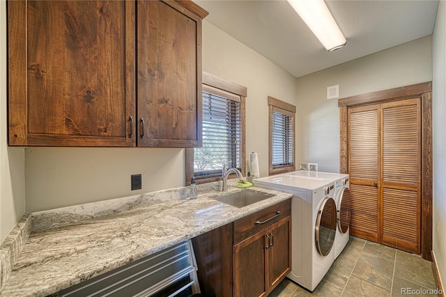 washroom with cabinet space, visible vents, separate washer and dryer, and a sink