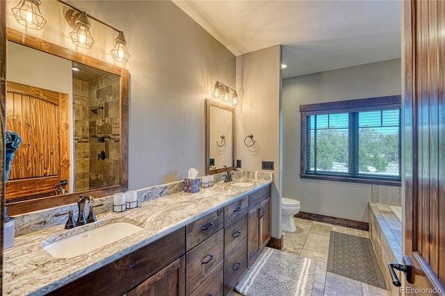 full bathroom with double vanity, a sink, toilet, and baseboards
