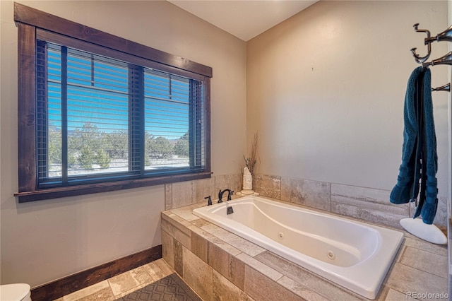 full bath featuring baseboards and a tub with jets