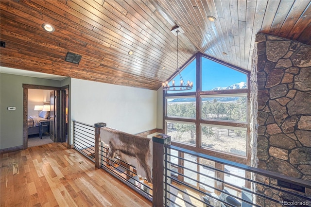 corridor featuring a chandelier, wooden ceiling, wood finished floors, an upstairs landing, and high vaulted ceiling