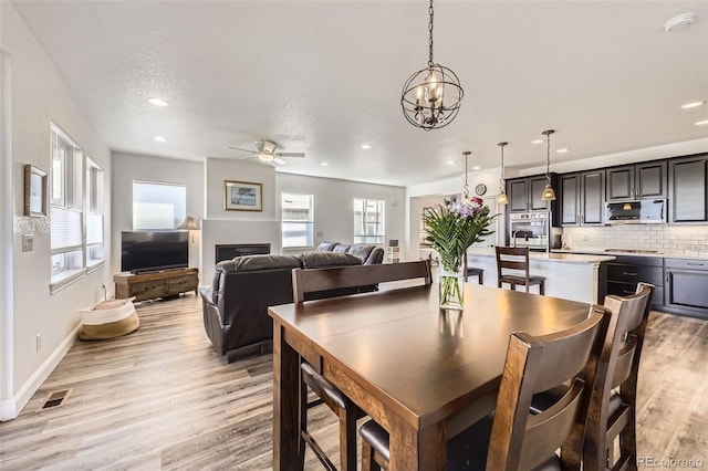 dining space with a ceiling fan, light wood finished floors, recessed lighting, a chandelier, and baseboards