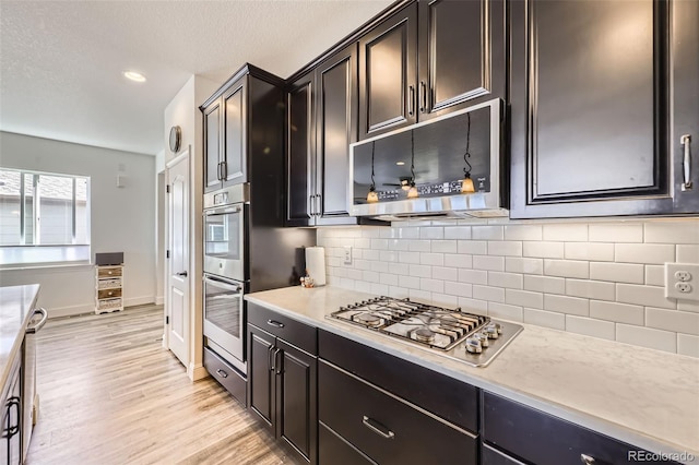 kitchen featuring appliances with stainless steel finishes, light wood-style floors, decorative backsplash, baseboards, and recessed lighting