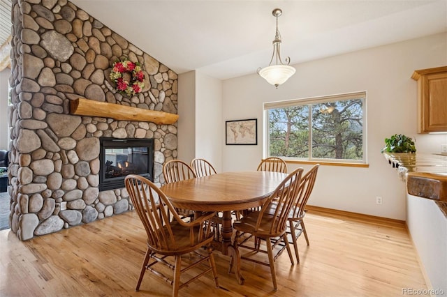 29004 Amerind Springs Trl, Pine, CO 80470 - dining area featuring light wood-style floors, a fireplace, and vaulted ceiling