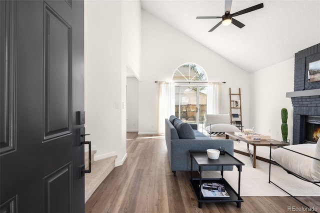 living room featuring stairway, a brick fireplace, a ceiling fan, and wood finished floors