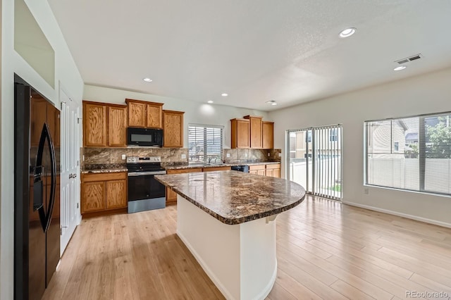 4414 Walden St, Denver, CO 80249 - kitchen featuring black appliances, a center island, tasteful backsplash, brown cabinetry, and recessed lighting