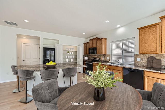 4414 Walden St, Denver, CO 80249 - kitchen featuring black appliances, decorative backsplash, a breakfast bar area, light wood-type flooring, and recessed lighting