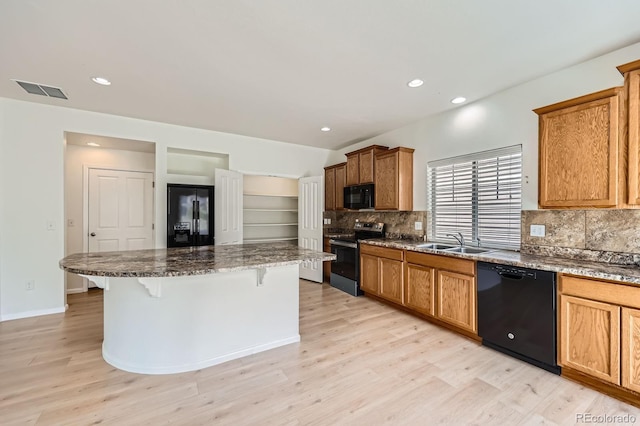 4414 Walden St, Denver, CO 80249 - kitchen with black appliances, backsplash, a breakfast bar, a kitchen island, and light wood-type flooring