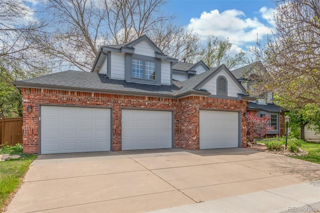 view of front of property with a garage, fence, roof with shingles, brick siding, and driveway