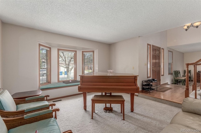 living area featuring carpet floors, a textured ceiling, visible vents, baseboards, and stairway