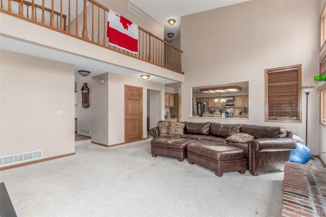 carpeted living area with baseboards, visible vents, and a high ceiling