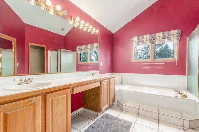 full bathroom featuring a sink, tile patterned floors, vaulted ceiling, double vanity, and a garden tub