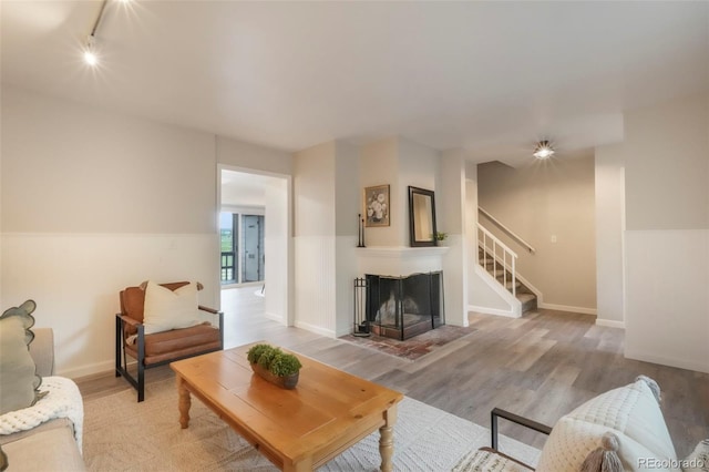 404 Raspberry Ln, Monument, CO 80132 - living room with track lighting, light wood-type flooring, stairs, baseboards, and a fireplace with flush hearth