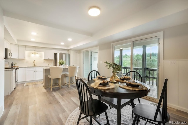 404 Raspberry Ln, Monument, CO 80132 - dining room featuring a raised ceiling, light wood-style floors, recessed lighting, and wainscoting
